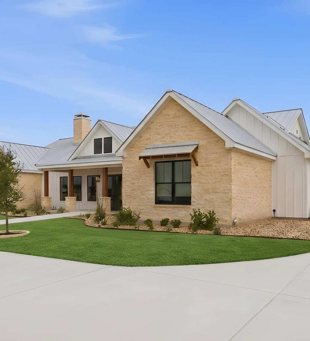 A finished Pioneer install at a new custom home in Seguin: sod lawn, tree well, and a gravel bed with drought-tolerant plantings against limestone