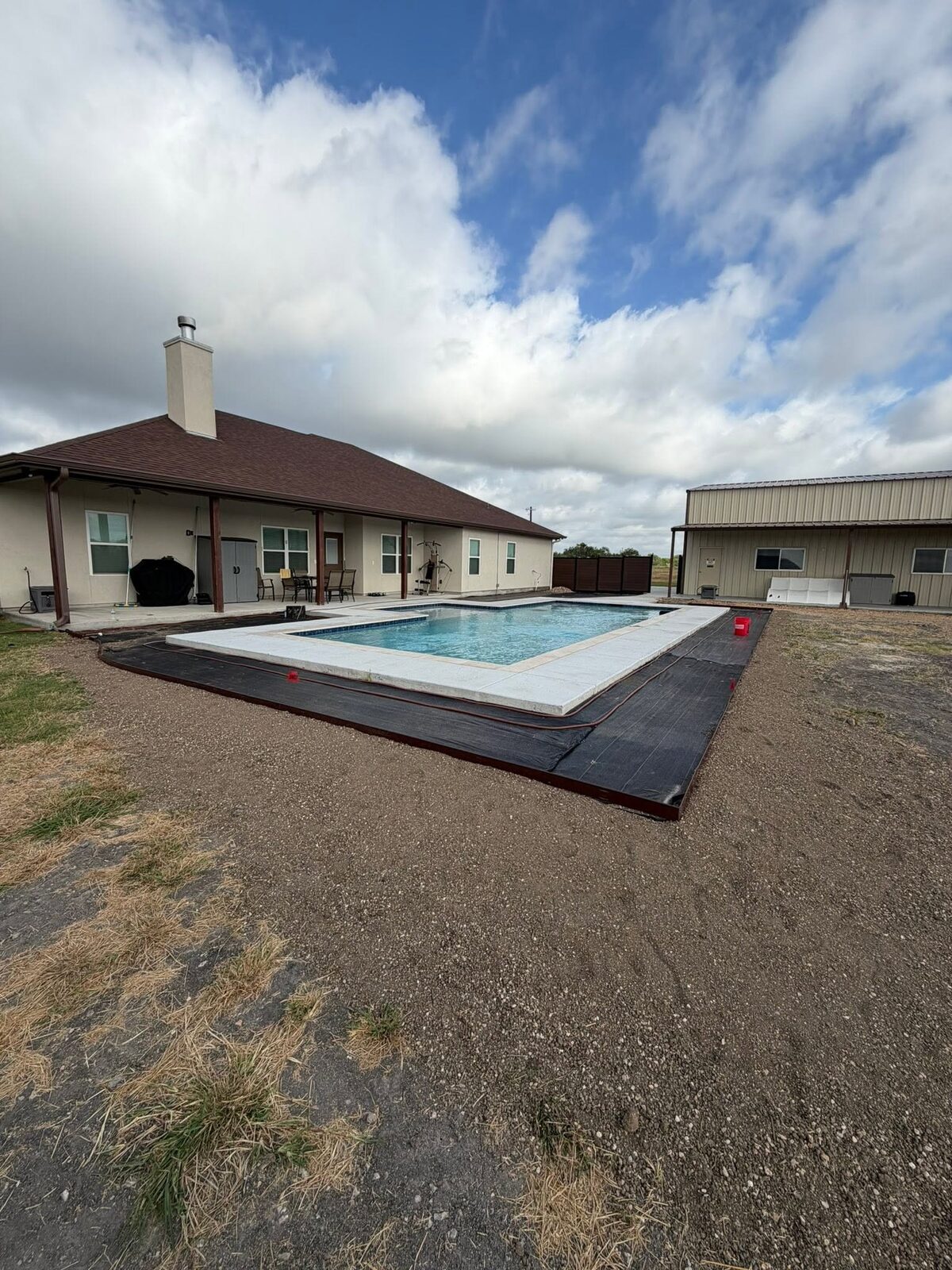 A Pioneer job in progress: weed barrier and steel edging staked out around a new pool deck before stone and planting