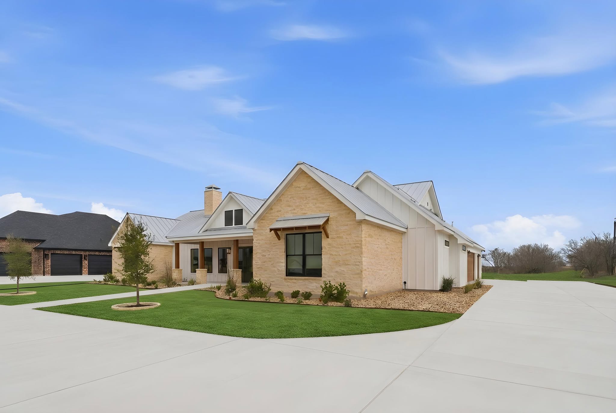 A finished Pioneer install at a new custom home in Seguin: sod lawn, tree well, and a steel-edged gravel bed with drought-tolerant plantings against limestone