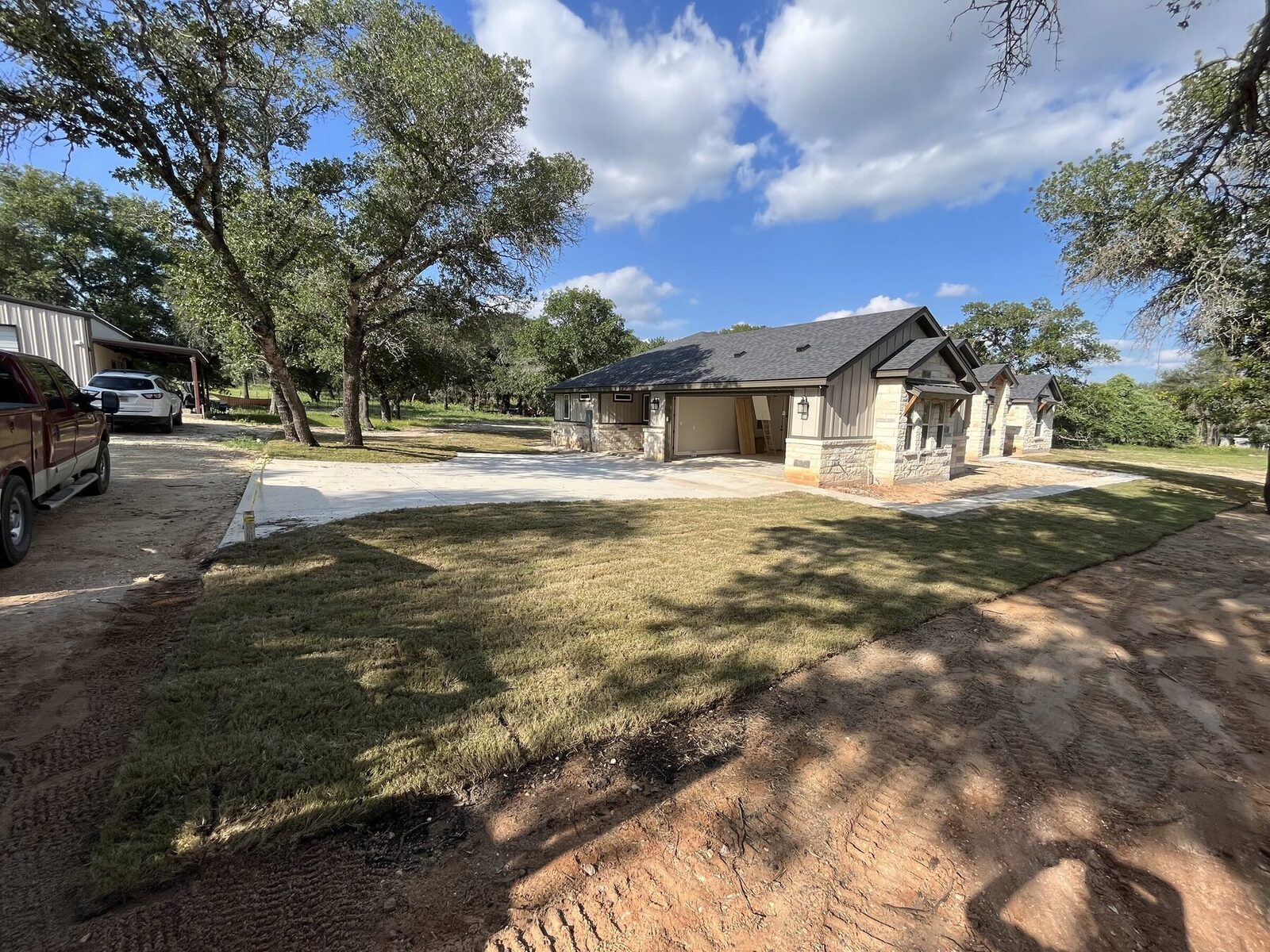 New sod across the front of the home with the concrete drive and covered entry beyond