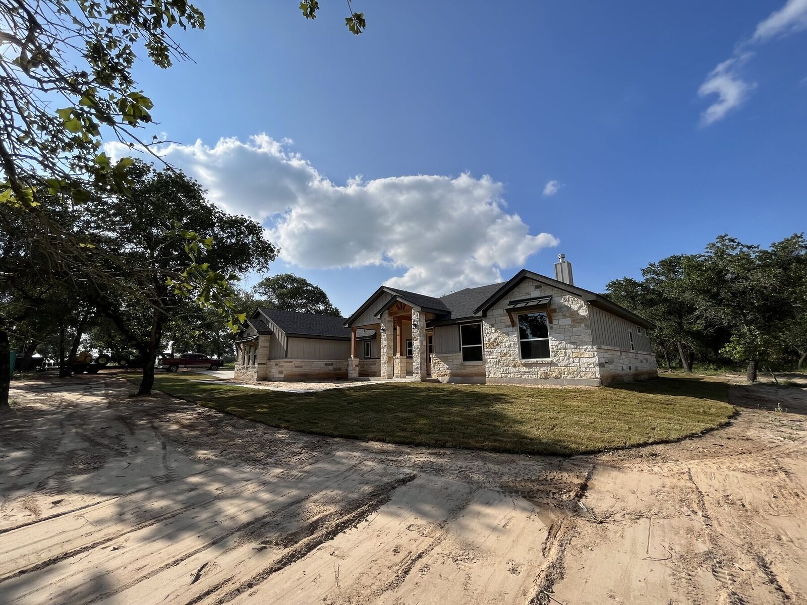 A limestone country home with fresh sod laid in a curved apron around the front and bare graded ground beyond
