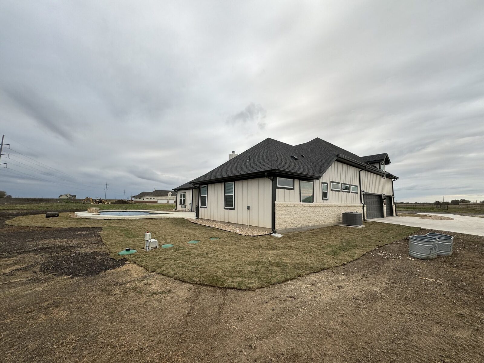 The side of the property showing the sod apron with irrigation valve boxes set into the lawn and open country beyond