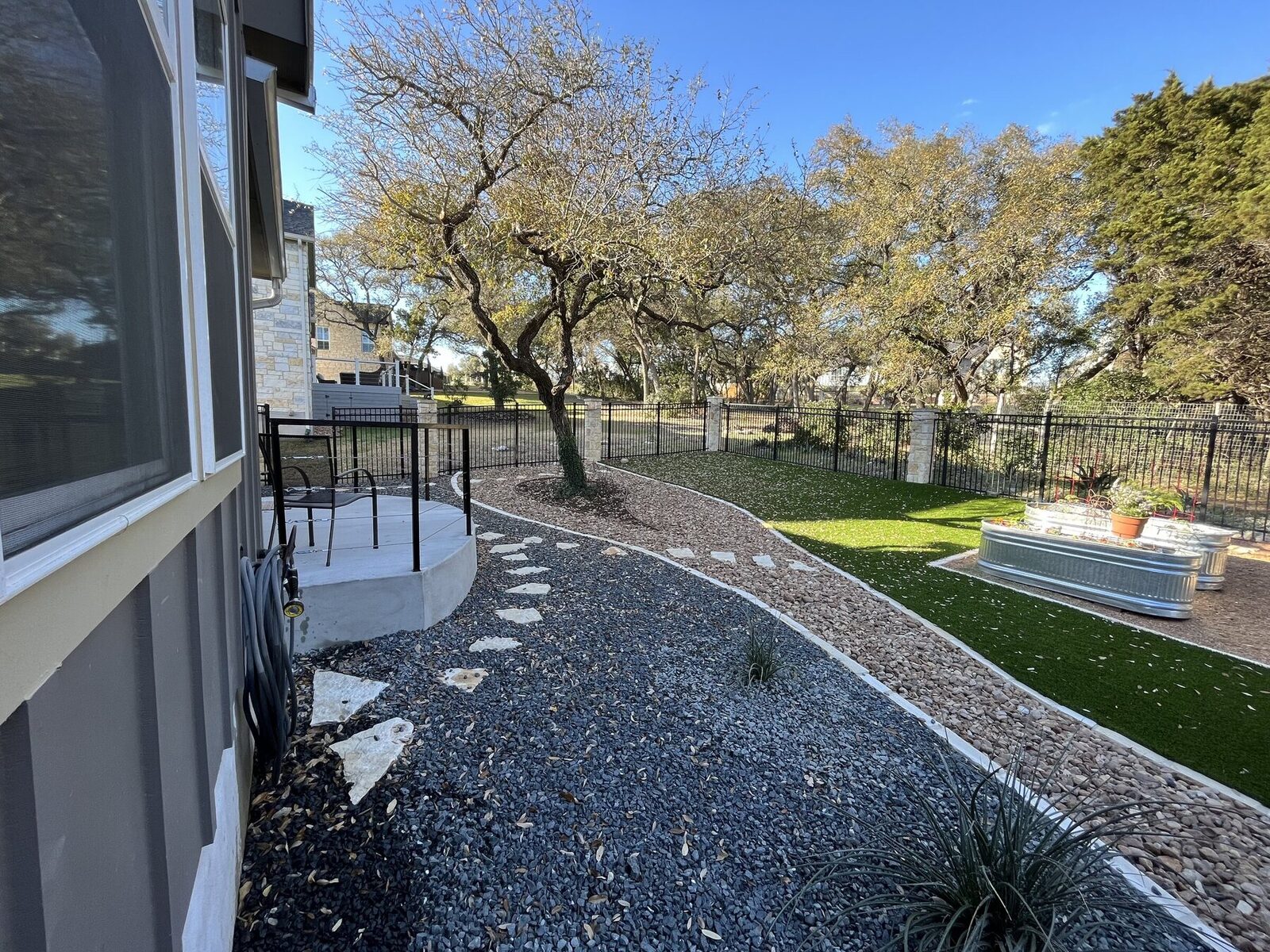 Flagstone stepping path running from the patio through gravel beds toward the fence line under mature trees